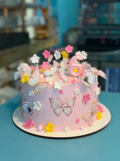 Tarta rosa de cumpleaños con mariposas, flores de azúcar y un número 6