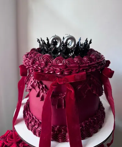 Tarta vintage granate con volantes de crema, lazos de terciopelo y una corona negra